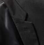 Close-up of a black tuxedo jacket showing fabric texture and pocket detail.