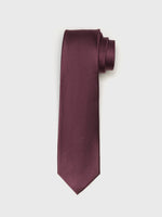 A burgundy tie with a textured pattern, rolled at the top and hanging down.