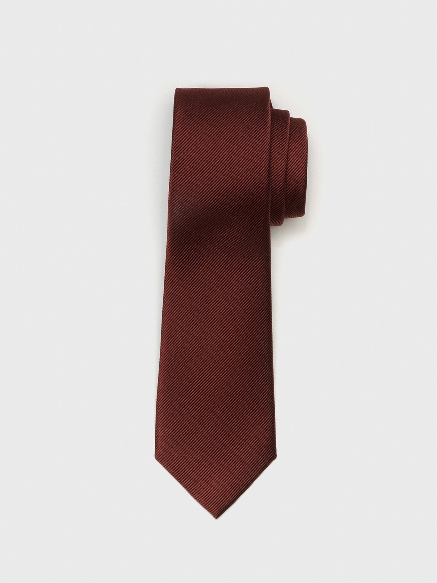 Burgundy tie with a textured pattern, rolled up on a white background.
