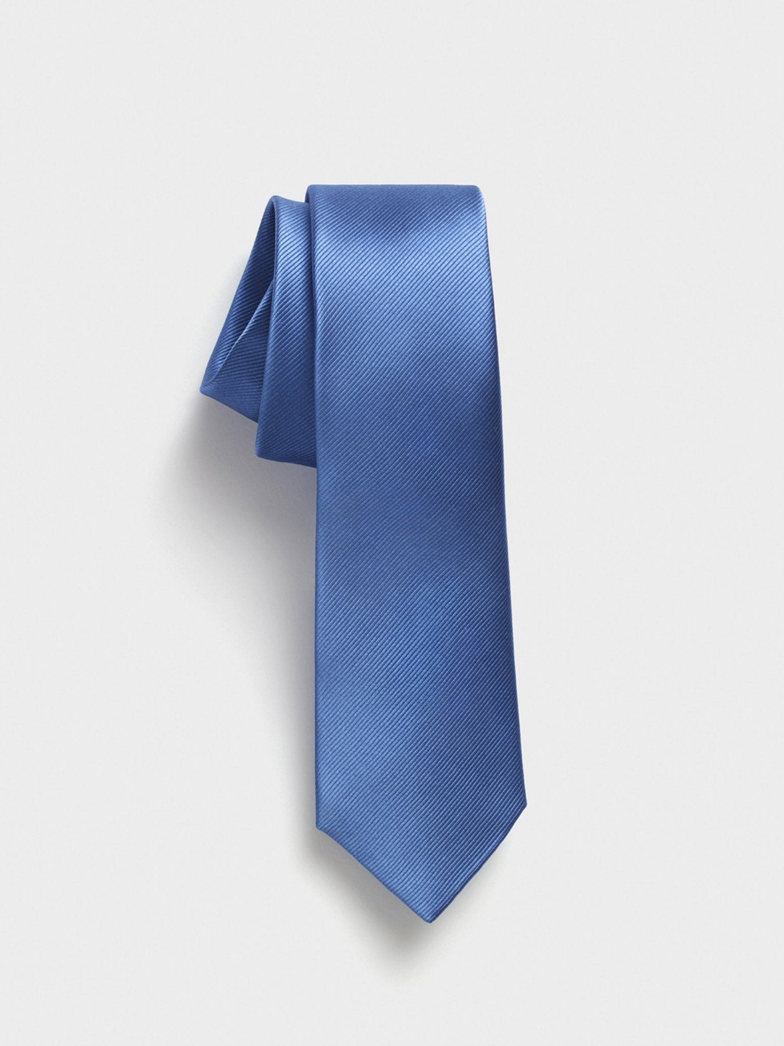 Solid blue tie with a textured pattern, draped elegantly.