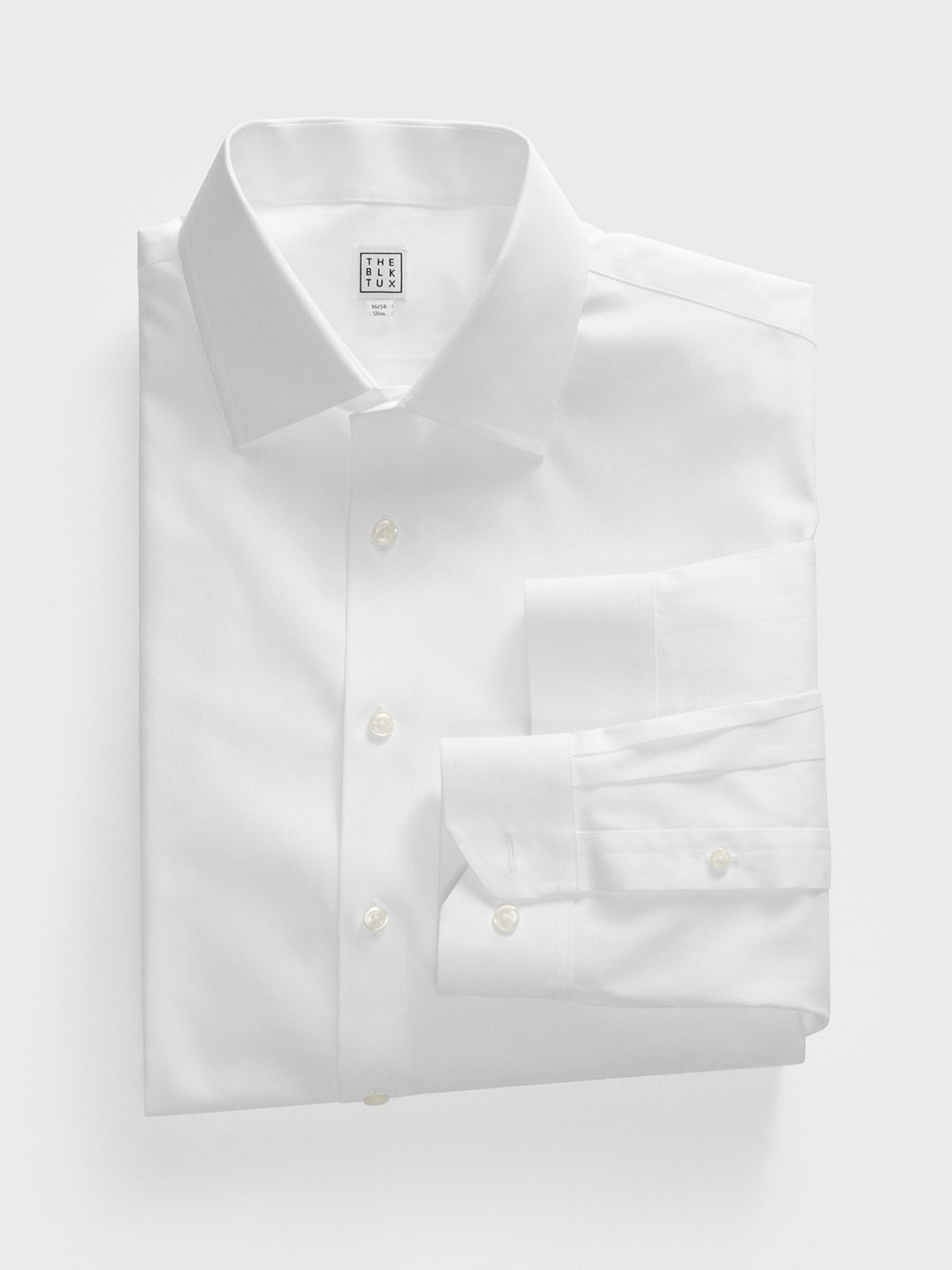 Folded white dress shirt with a collar and buttons, featuring a tag.