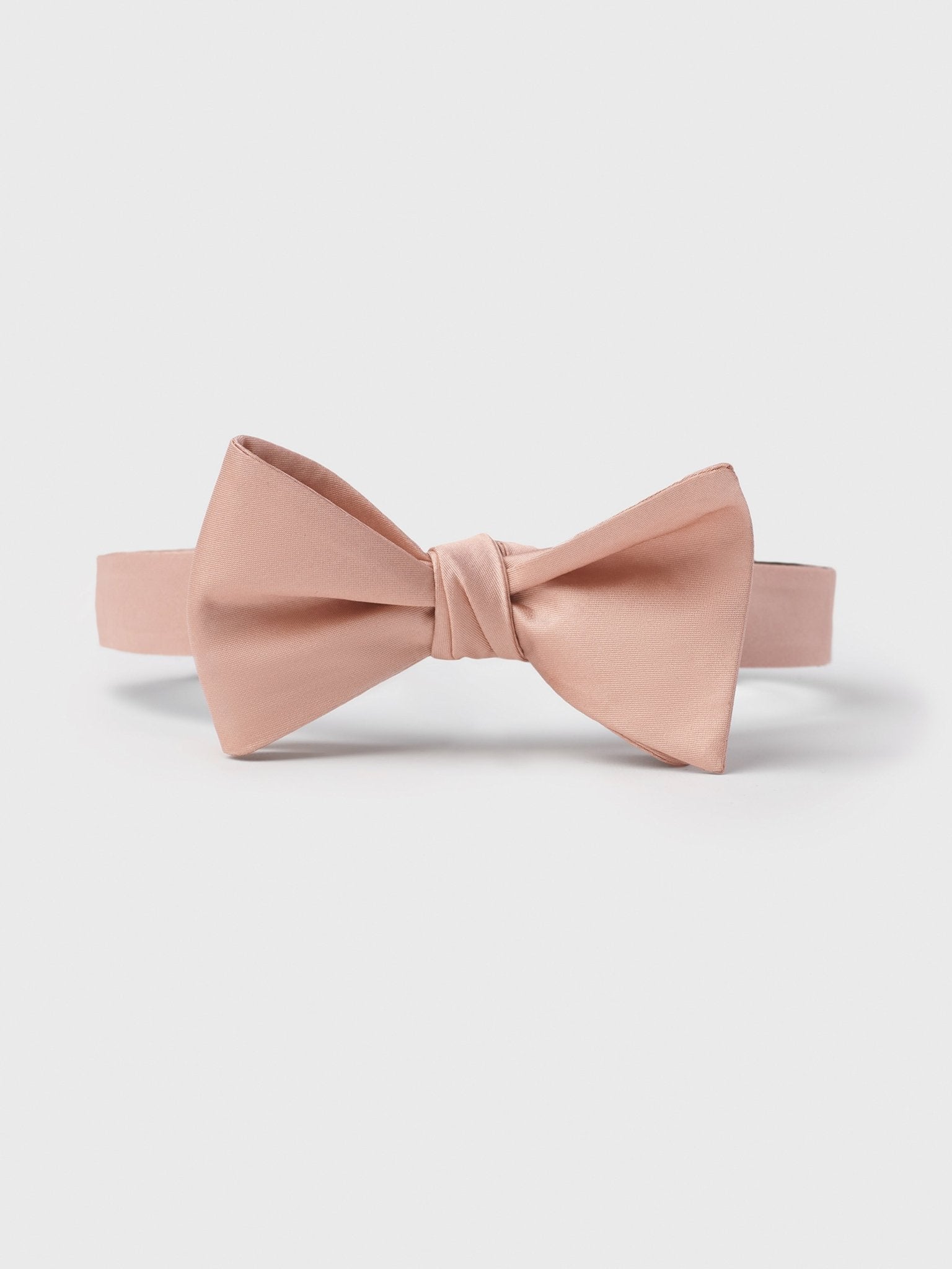 Light pink bow tie with a smooth finish and adjustable strap.