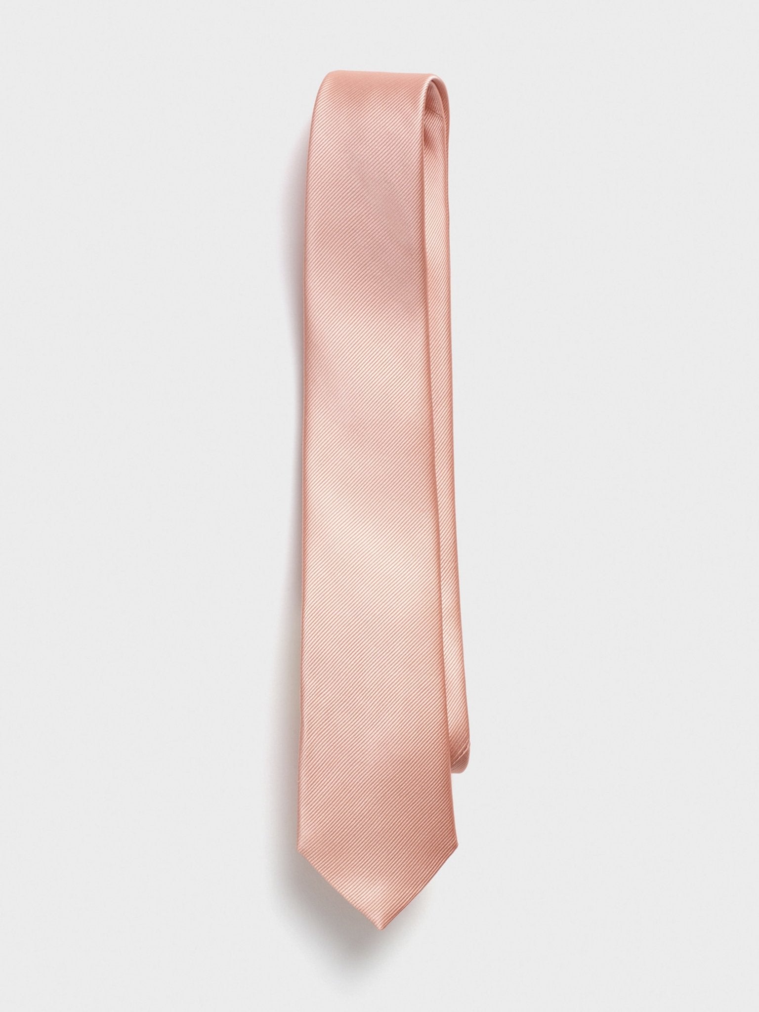 Light pink tie with a textured pattern, hanging against a white background.