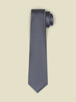 Navy tie with a textured pattern, rolled at the top, against a light background.