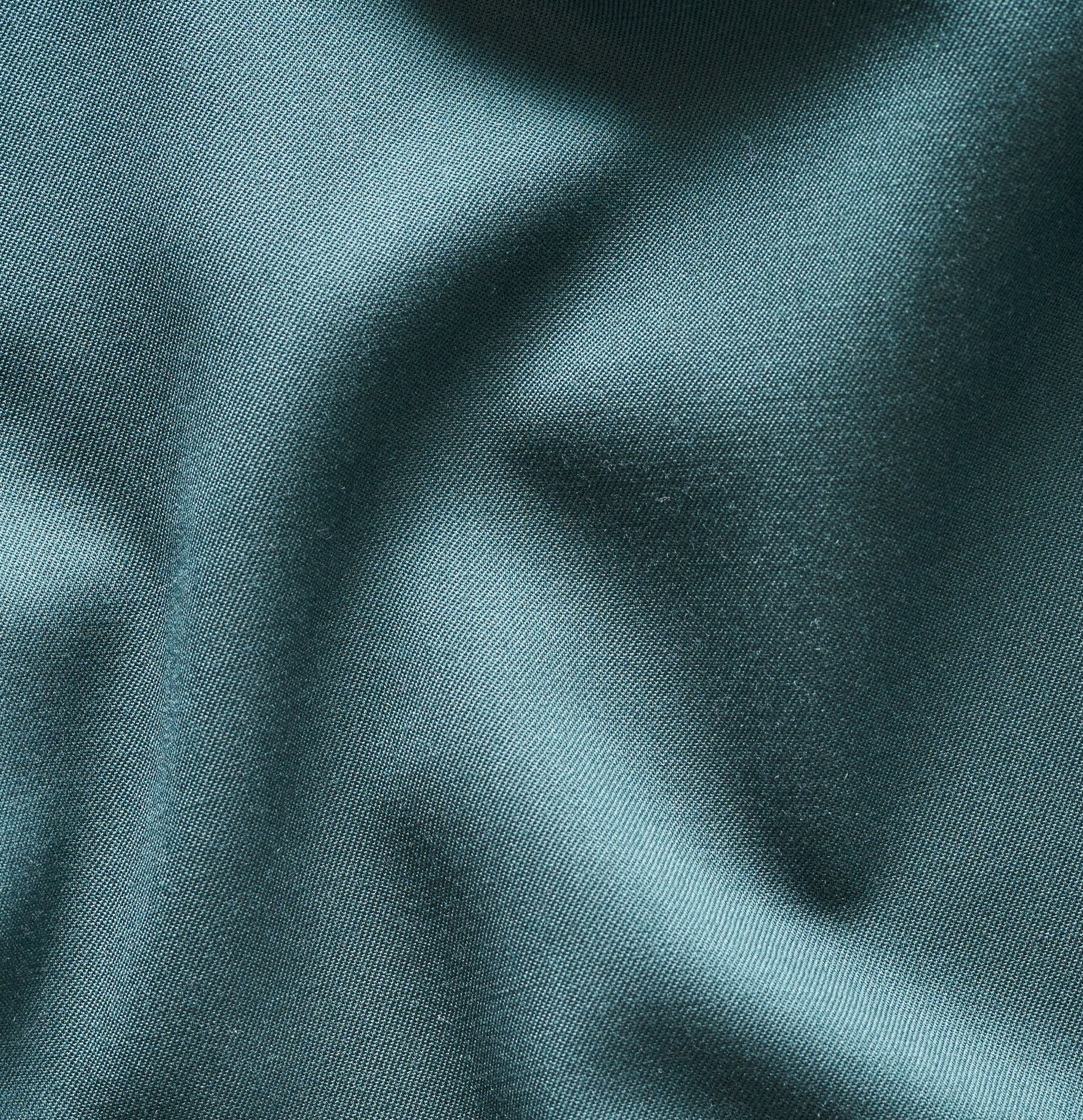 Close-up of teal fabric with a smooth texture and subtle sheen.
