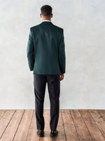 Man wearing a green suit jacket and black pants, viewed from the back.