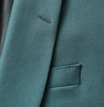 Close-up of a teal suit jacket showing fabric texture and a pocket.