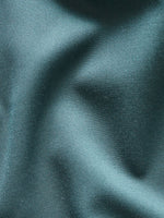 Close-up of teal fabric with a smooth texture and subtle folds.