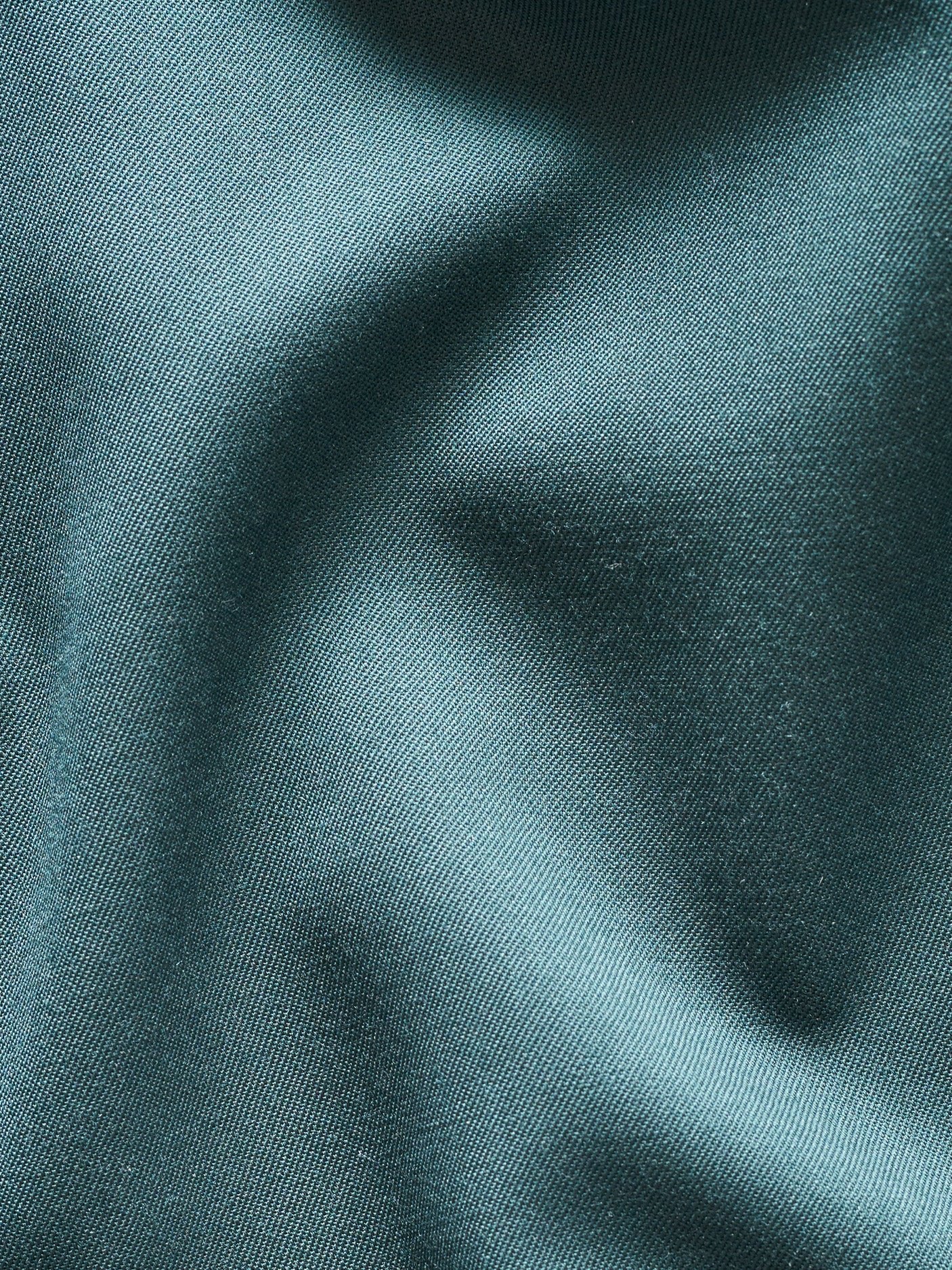 Close-up of teal fabric with a smooth texture and subtle folds.