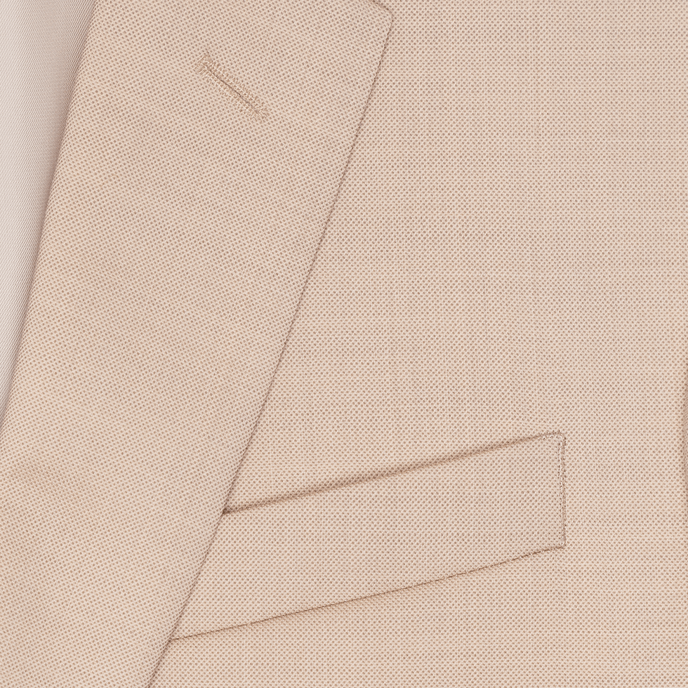 Close-up of a light beige suit jacket with a pocket and lapel.