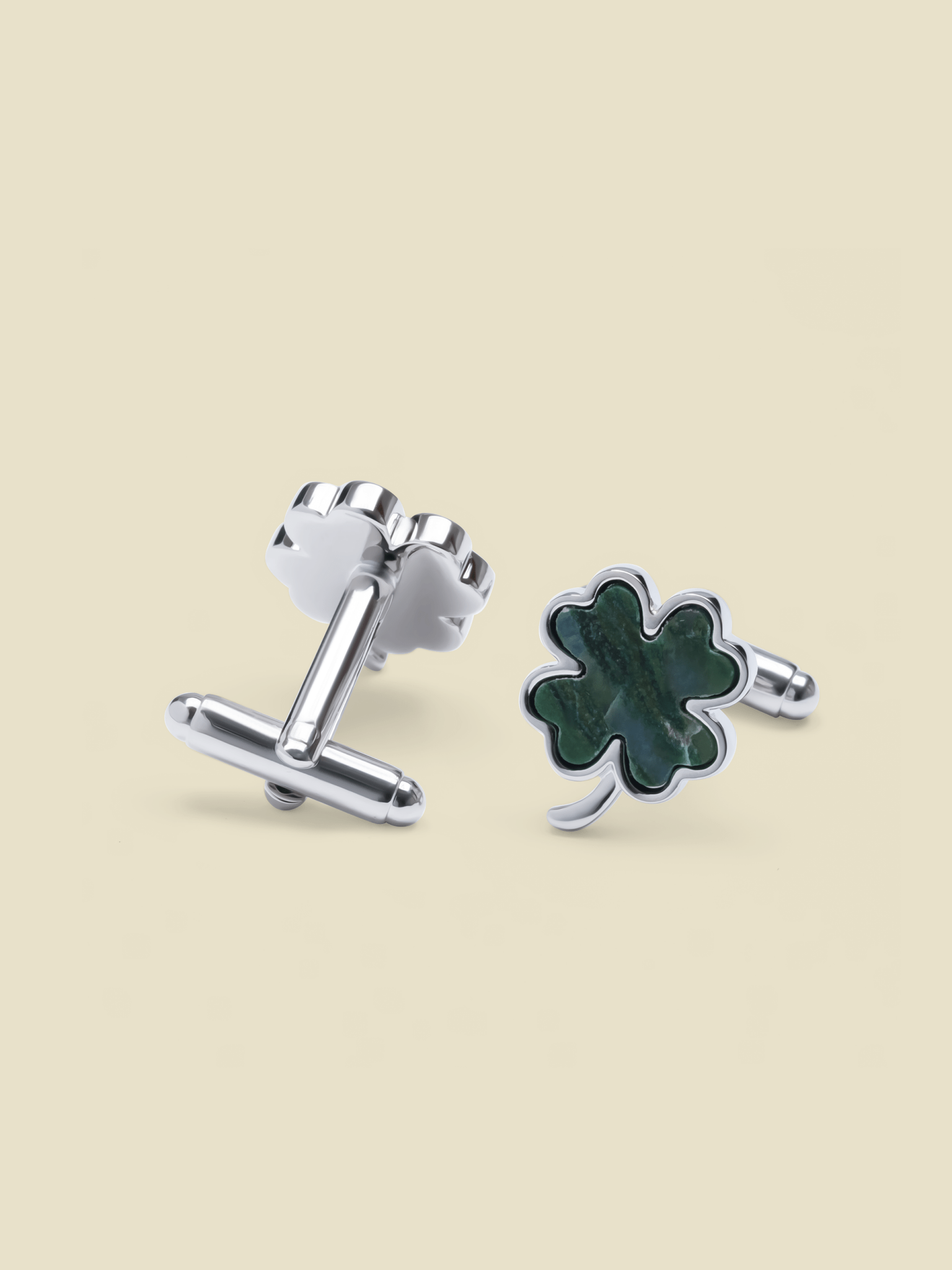 Silver cufflinks shaped like a clover with a green stone inlay.