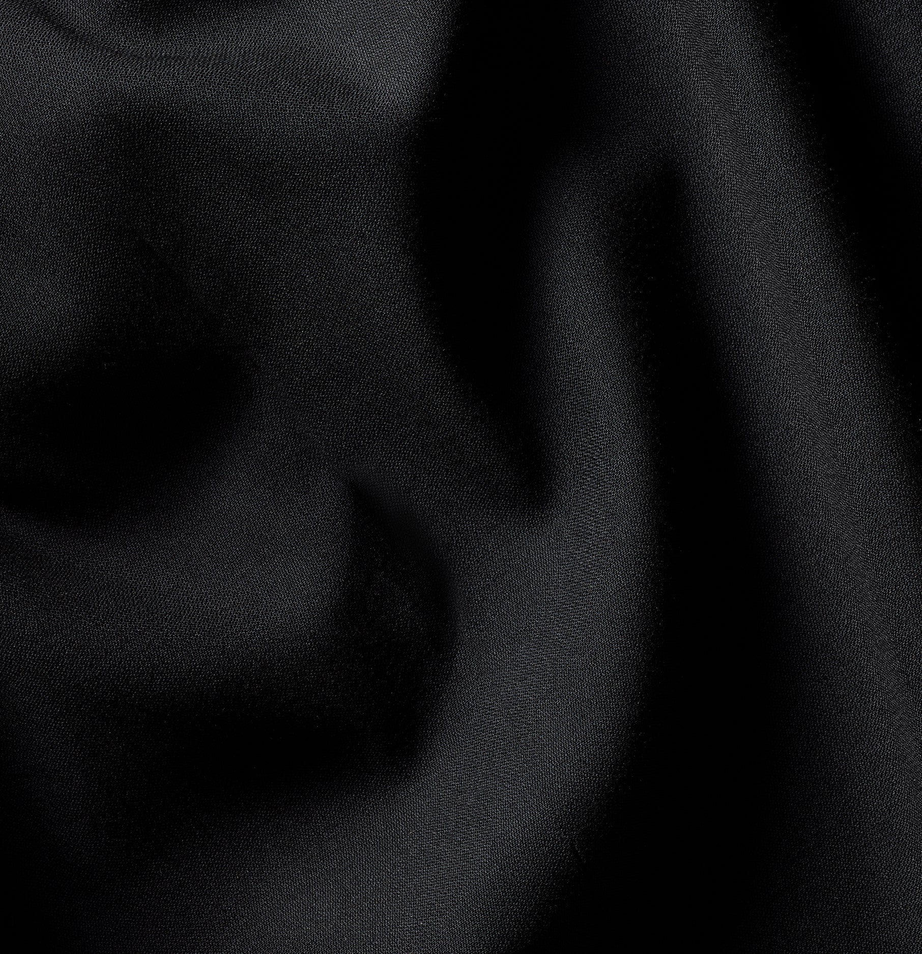 Close-up of black fabric with a smooth texture and subtle folds.