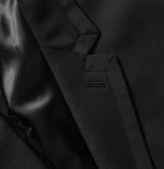 Close-up of a black tuxedo jacket's fabric and stitching details.