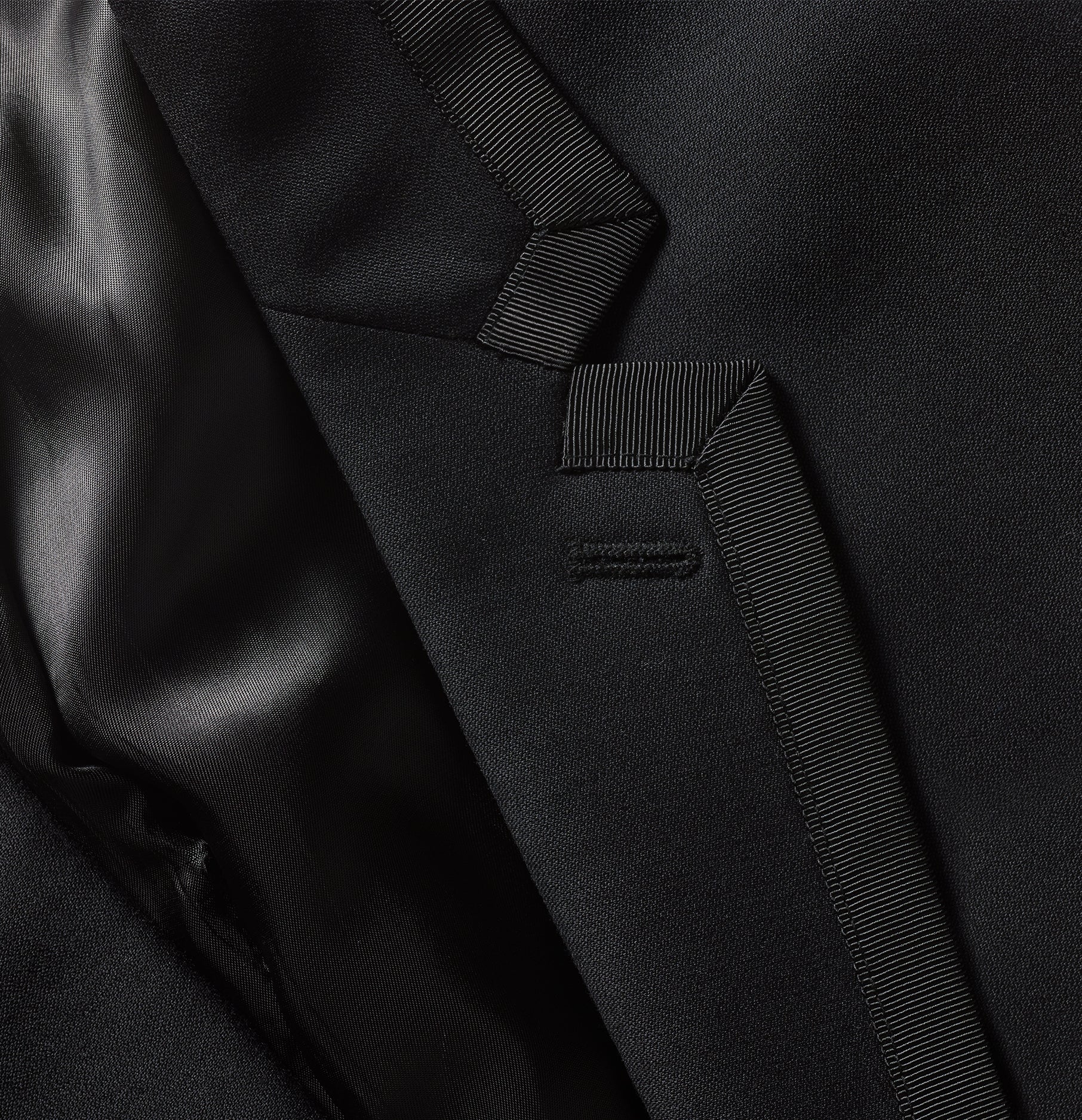 Close-up of a black tuxedo jacket's fabric and stitching details.