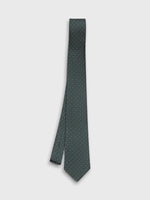 Dark green tie with white polka dots on a white background.