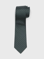 Dark green tie with small white polka dots, rolled up on a white background.