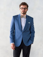 Man wearing a blue tuxedo jacket with a bow tie and glasses.