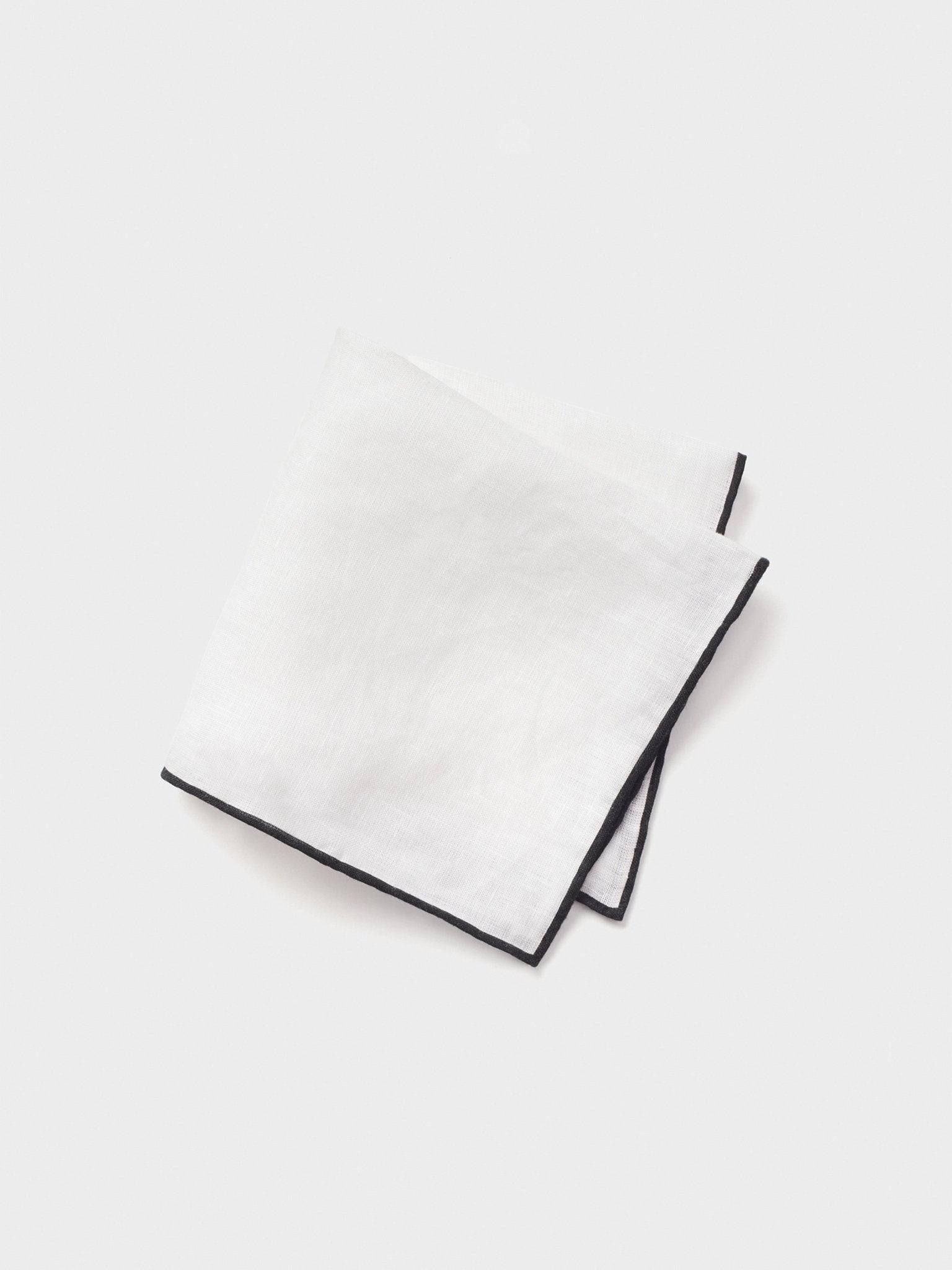 White handkerchief with a black border folded in a triangular shape.