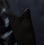 Close-up of a navy suit jacket with a black lapel and shiny lining.