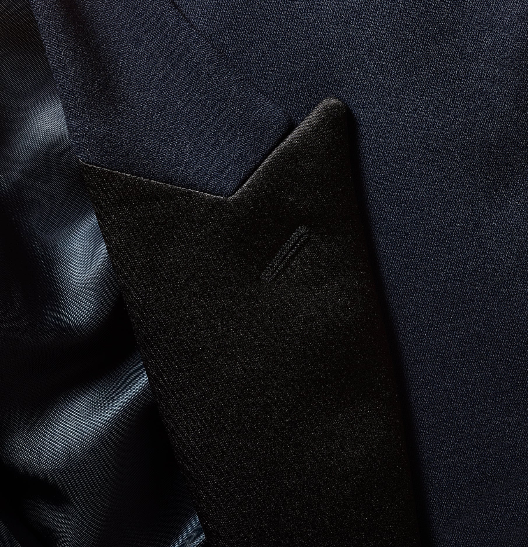 Close-up of a navy suit jacket with a black lapel and shiny lining.