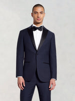 Man in a navy tuxedo with a black bow tie and white shirt.