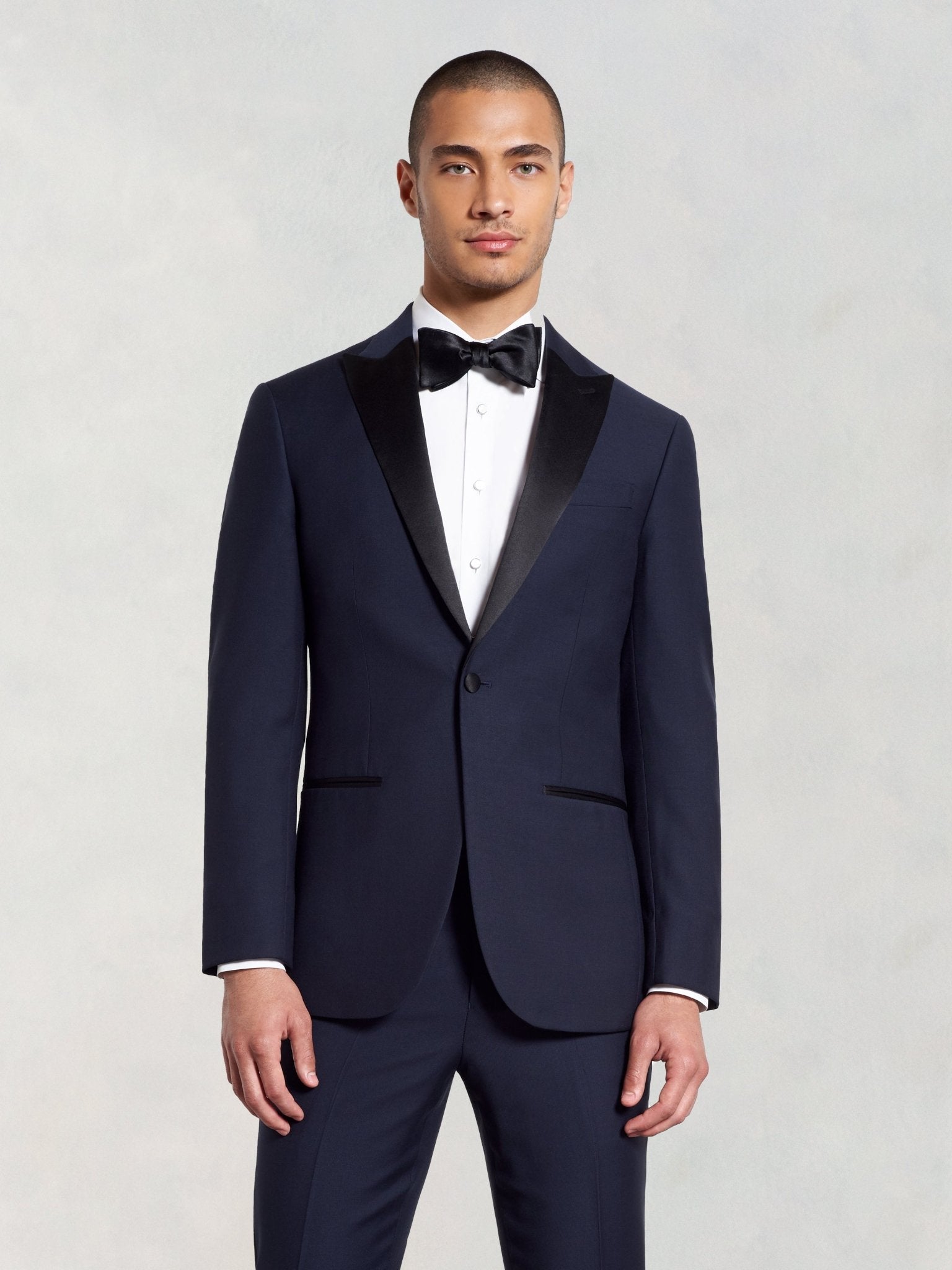 Man in a navy tuxedo with a black bow tie and white shirt.