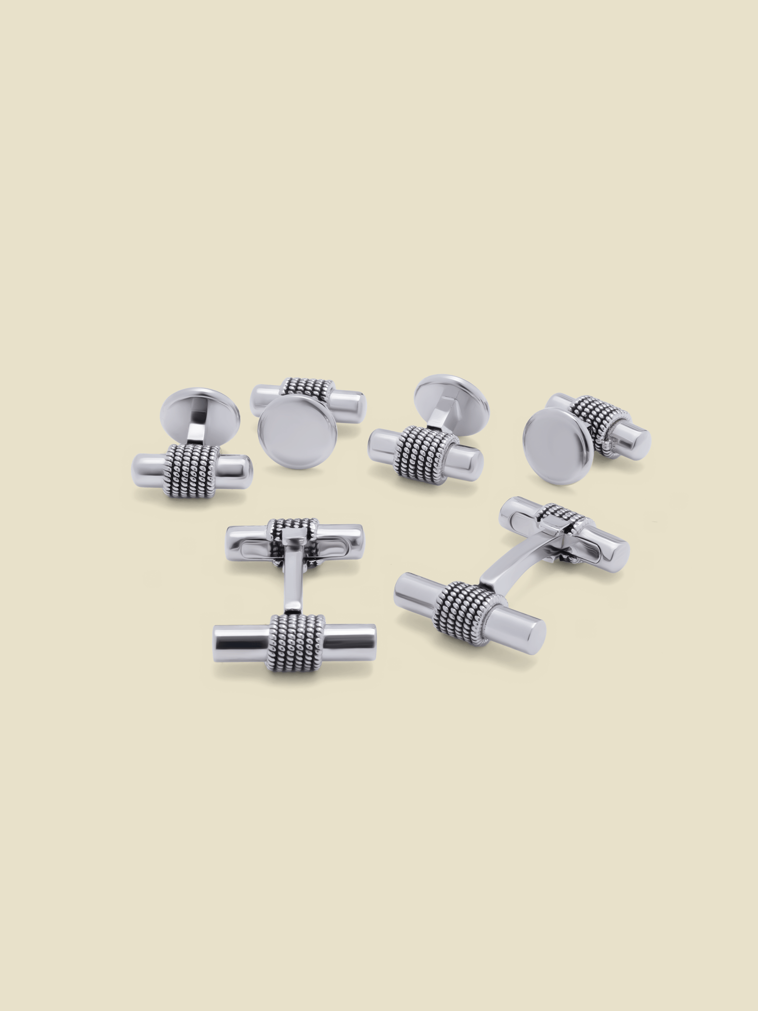 Set of silver cufflinks arranged on a light background.