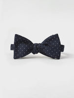 Navy blue bow tie with white polka dots on a plain background.