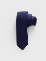 Navy tie rolled up on a light gray background.