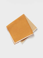 Two fabric pocket squares, one orange and one beige, stacked on a white background.