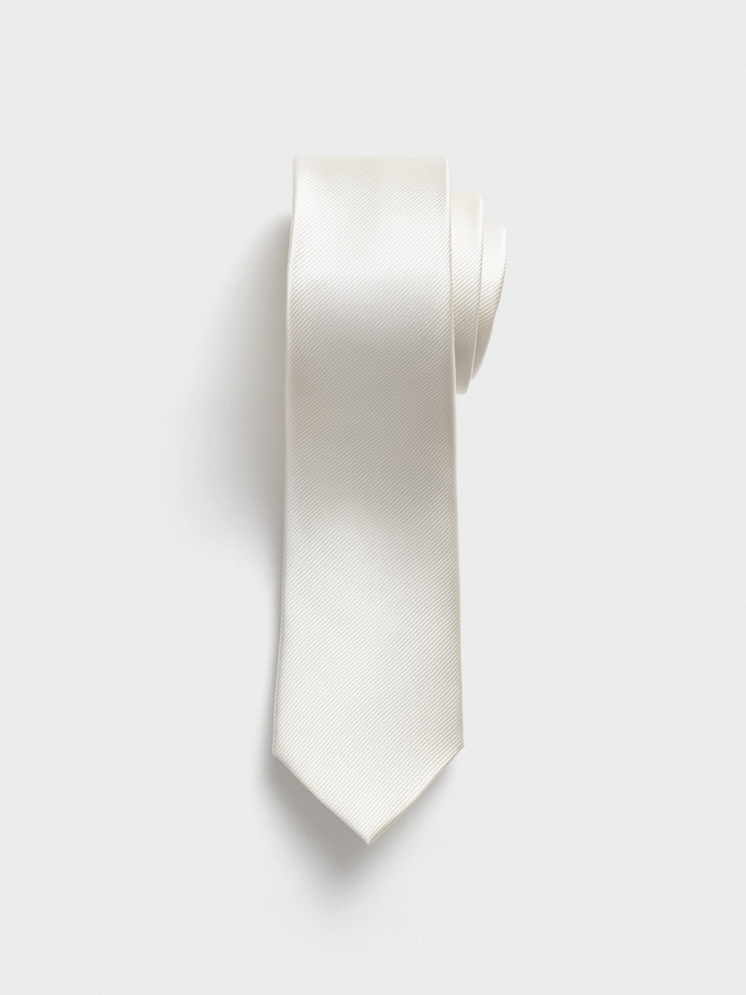 A rolled white tie with a textured pattern on a light background.