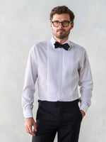 Man wearing a white tuxedo shirt with a black bow tie and black pants.