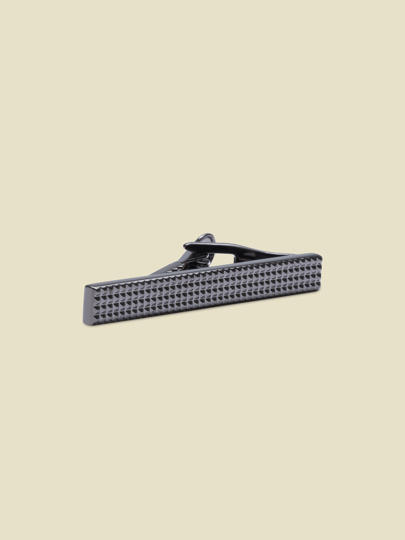 Black tie clip with a textured surface on a light background.