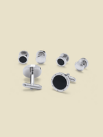 Set of silver cufflinks with black accents on a beige background.
