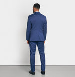 Man wearing a blue suit, viewed from the back, standing on a gray floor.