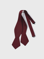 Burgundy bow tie with a textured pattern, lying flat on a white background.