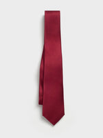 Solid burgundy tie hanging against a white background.