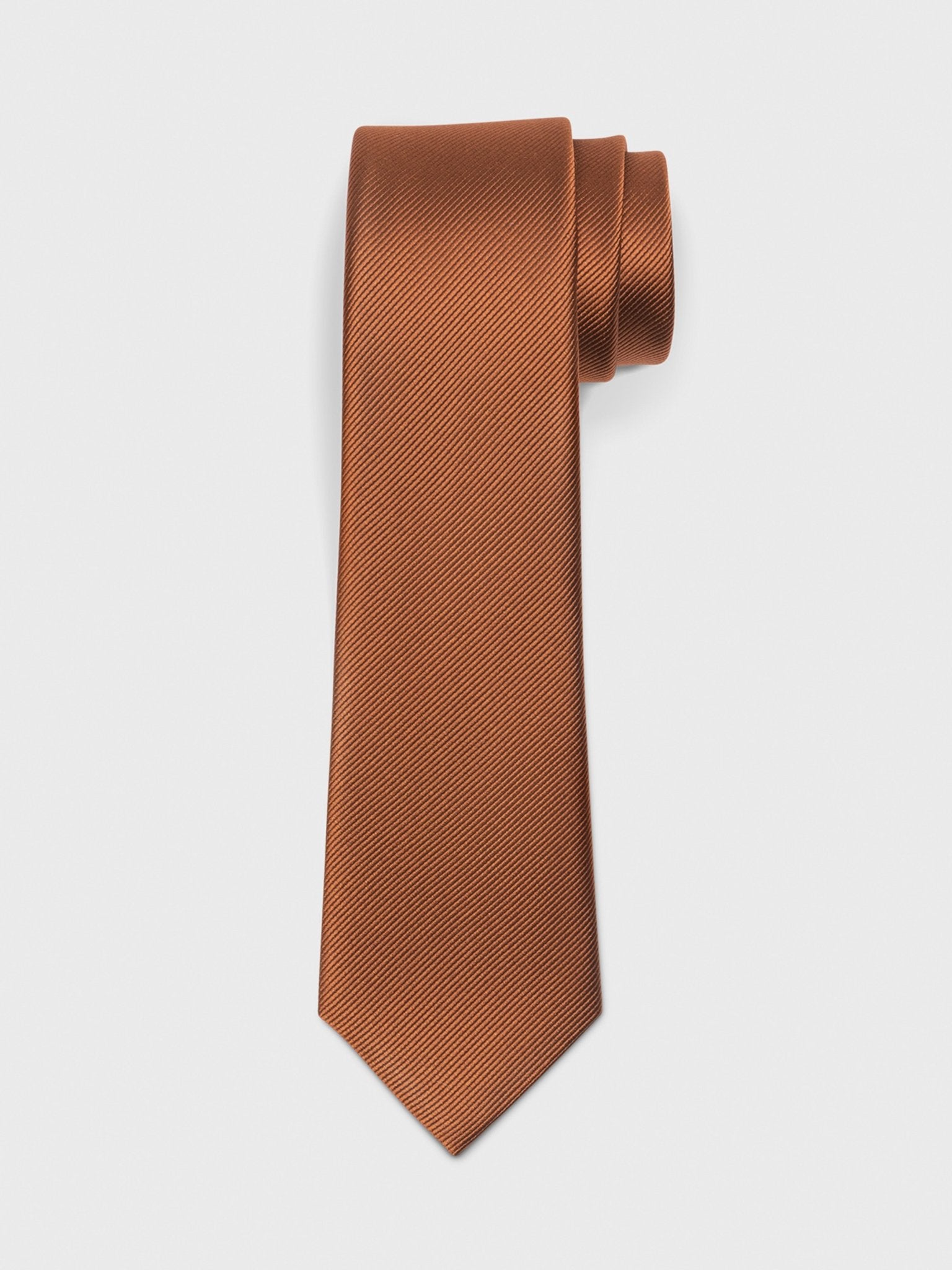 Brown textured tie rolled and resting on a white background.