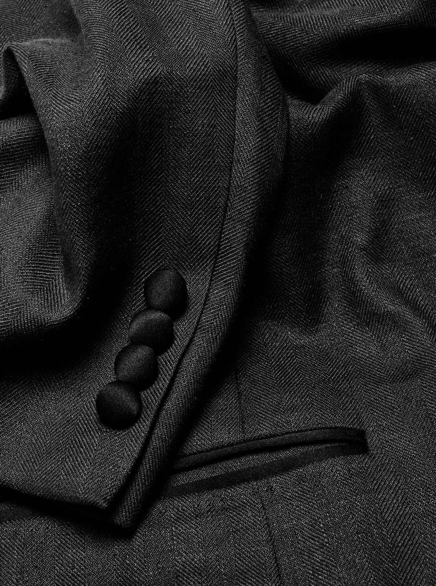 Close-up of a black tuxedo jacket showing fabric texture and buttons.