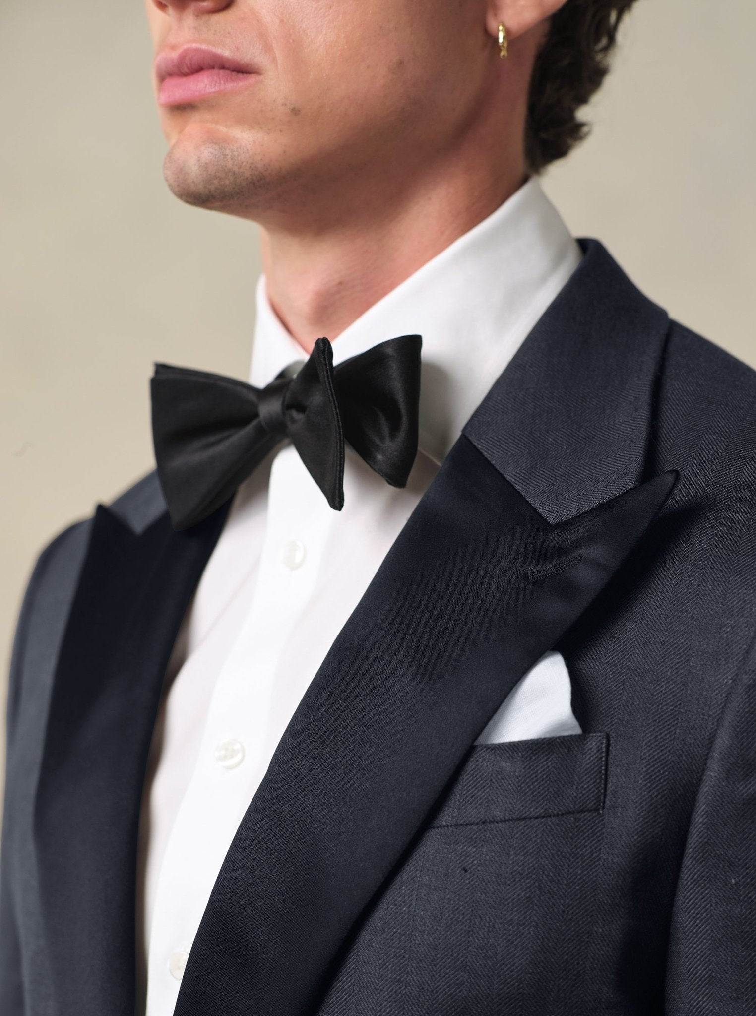 Close-up of a man wearing a black tuxedo with a bow tie and white shirt.