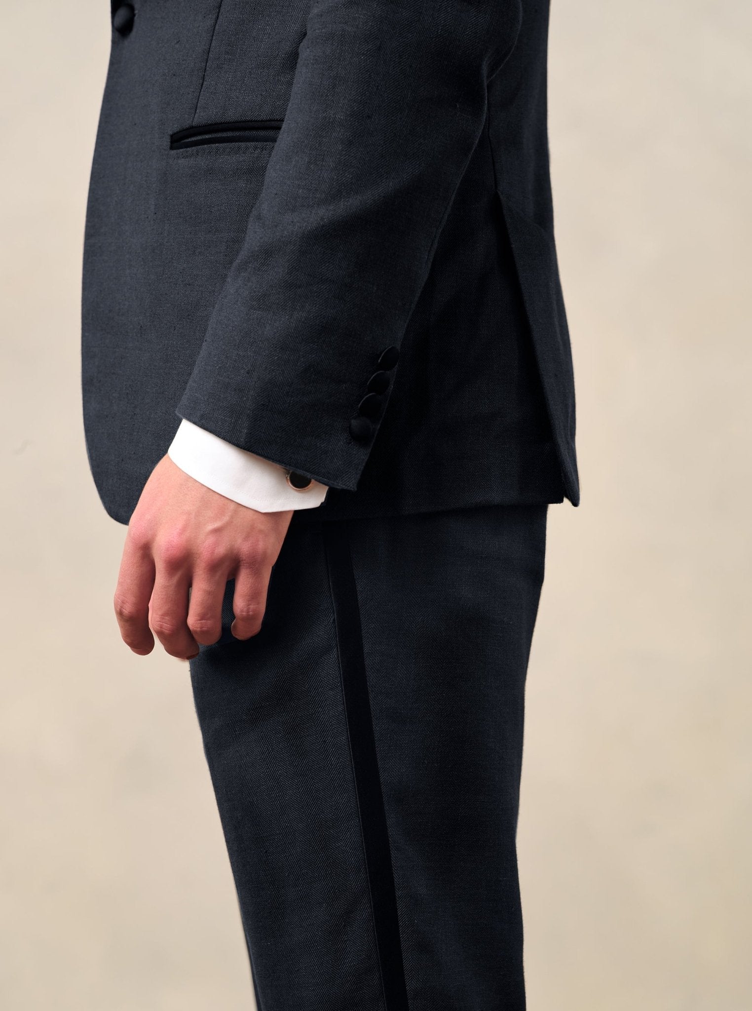 Close-up of a man's hand in a dark suit with a white shirt cuff visible.