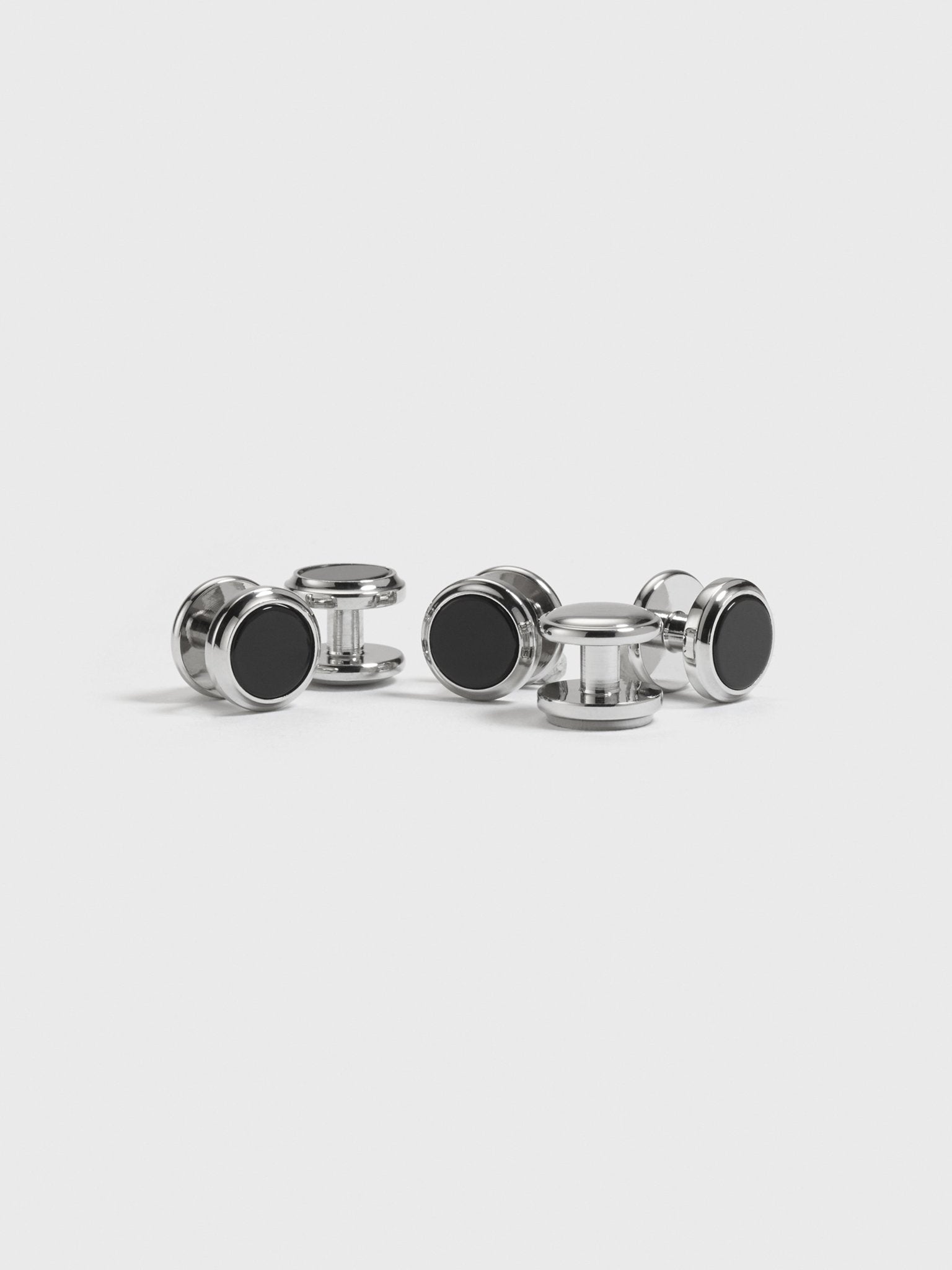 Four pairs of silver cufflinks with black centers on a white background.