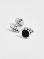 Silver cufflinks with black circular insets on a white background.