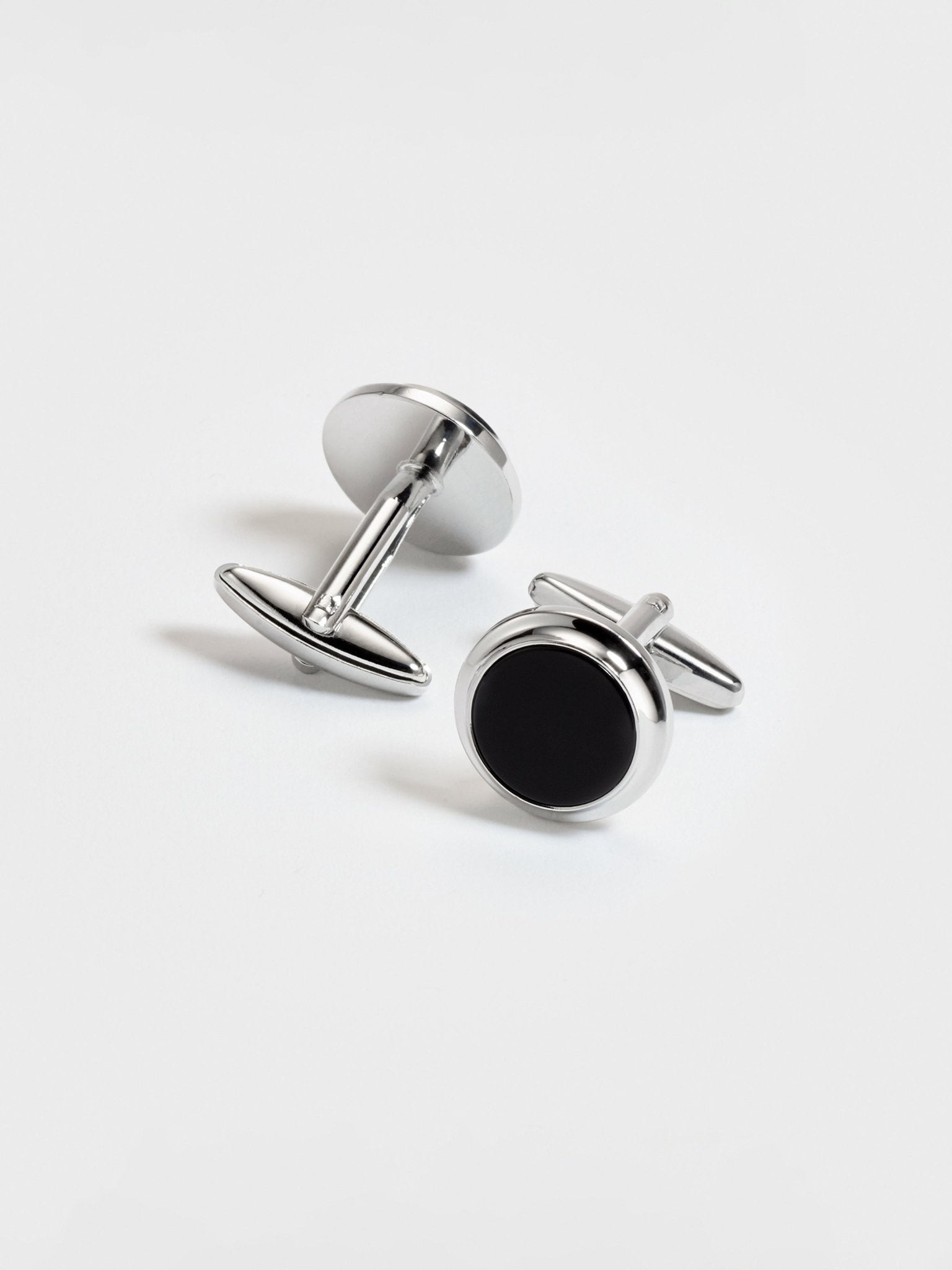Silver cufflinks with black circular insets on a white background.