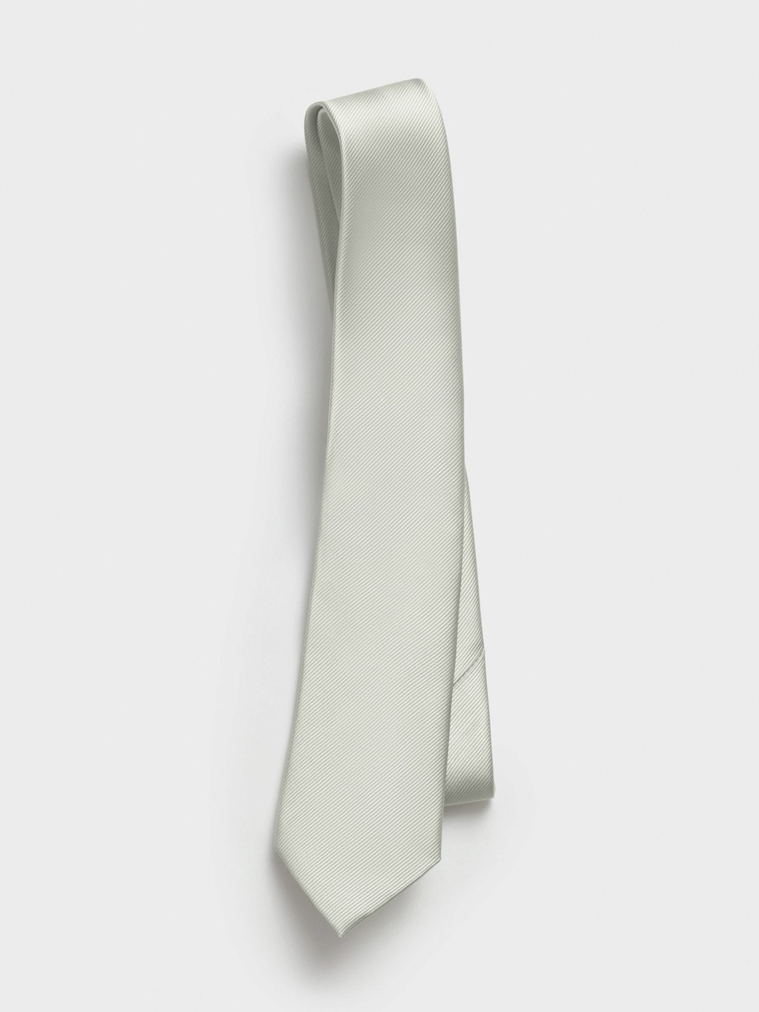 Light grey tie with a textured pattern hanging against a white background.