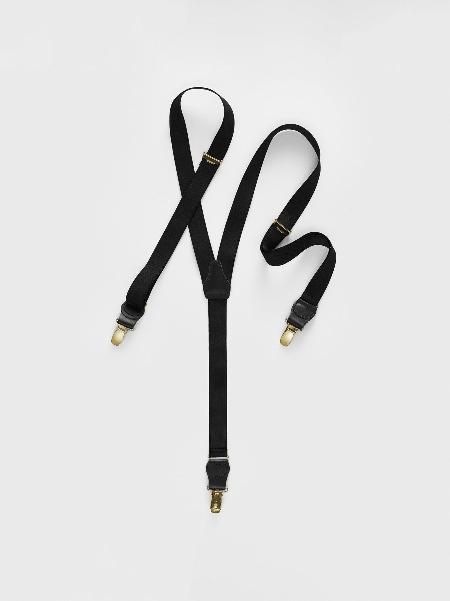 Black suspenders with gold clips on a white background.