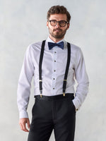 Man in a white shirt with black suspenders and a blue bow tie.