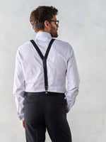 Man wearing a white shirt with black suspenders and black pants, viewed from the back.