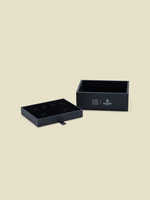 Open black box with a removable tray for holding items, featuring a logo.