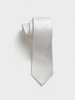 A white tie with a textured pattern, rolled up against a plain background.